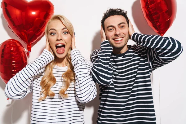 Alegre Pareja Cubriéndose Las Orejas Mientras Posan Con Globos Cardíacos — Foto de Stock