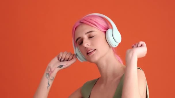 Μια Θετική Νεαρή Γυναίκα Ροζ Μαλλιά Ακούει Μουσική Χρησιμοποιώντας Ακουστικά — Αρχείο Βίντεο