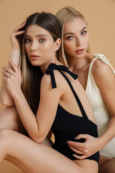 Twee Sensuele Elegante Vrouwen Zwempakken Die Samen Poseren Geïsoleerd Beige — Stockfoto