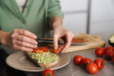 Mutfakta avokado ve domatesli nefis bruschetta yapan kadın, ellerini kapat.