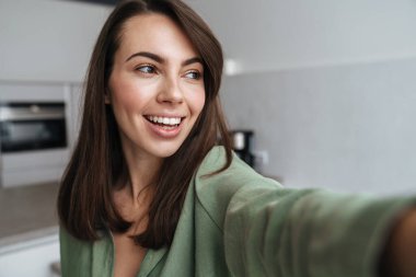 Mutfakta selfie çekerken gülümseyen genç bir kadın.