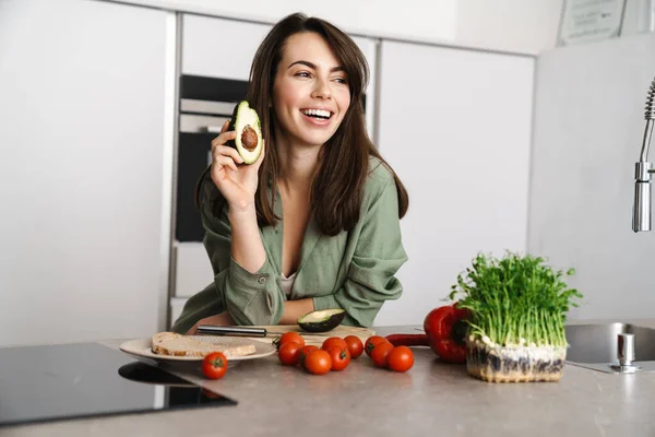 Fröhlich Schöne Frau Zeigt Avocado Während Sie Salat Der Heimischen — Stockfoto
