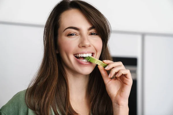 Joyful Brunette Woman Smiling While Eating Avocado Home Kitchen — Stock Photo, Image