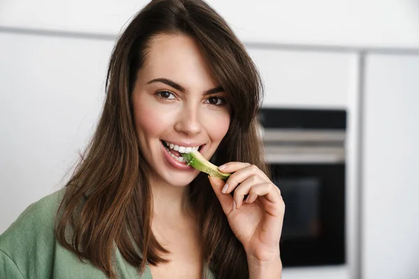 Mulher Morena Alegre Sorrindo Enquanto Come Abacate Cozinha Doméstica — Fotografia de Stock