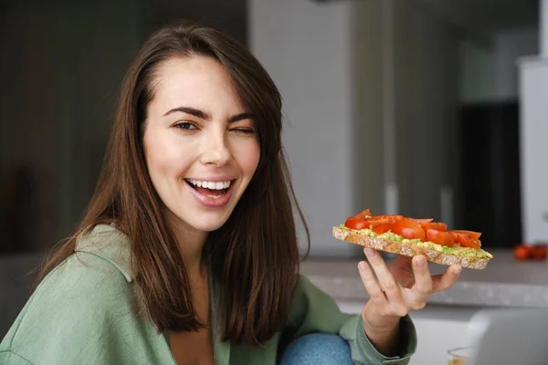 Junge Glückliche Frau Zwinkert Beim Essen Von Avocado Toast Der — Stockfoto