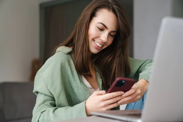 Allegro Bella Donna Utilizzando Telefono Cellulare Mentre Lavora Con Computer — Foto Stock