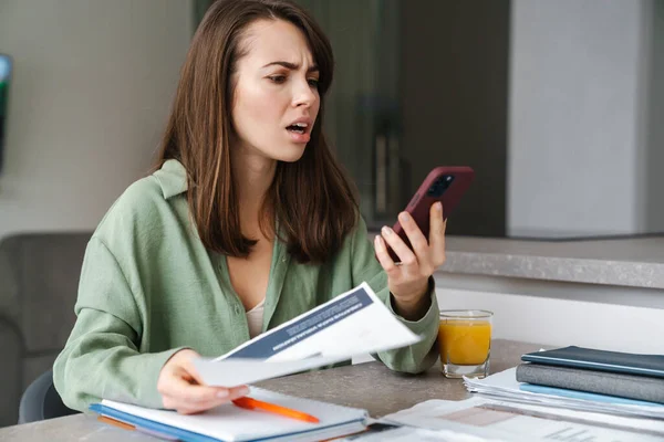 Mujer Joven Indignada Usando Teléfono Móvil Mientras Trabaja Con Papeles — Foto de Stock