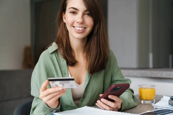 Mulher Sorridente Usando Celular Cartão Crédito Enquanto Senta Mesa Casa — Fotografia de Stock