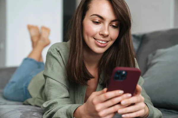 Young Smiling Woman Using Mobile Phone While Lying Sofa Home — Stock Photo, Image
