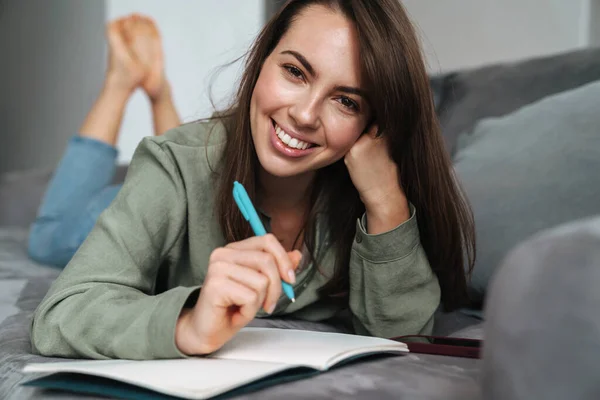 Young Smiling Woman Writing Notes While Lying Sofa Home — Stock Photo, Image