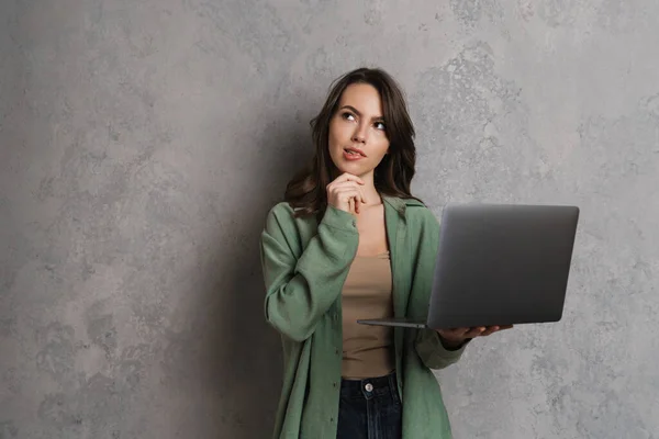 Intrigado Linda Garota Morena Pensando Usando Laptop Isolado Sobre Parede — Fotografia de Stock