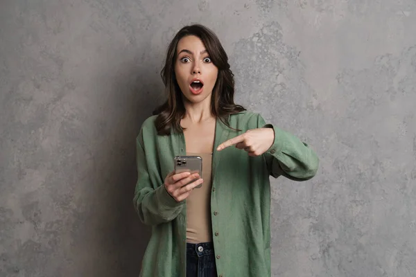 Chocado Bela Menina Segurando Apontando Dedo Para Celular Isolado Sobre — Fotografia de Stock