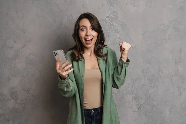 Muchacha Emocionada Haciendo Gesto Ganador Mientras Utiliza Teléfono Celular Aislado — Foto de Stock