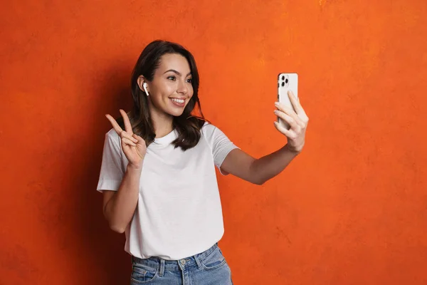 Щаслива Дівчина Навушниках Жестикулює Знак Миру Приймаючи Селфі Мобільний Телефон — стокове фото
