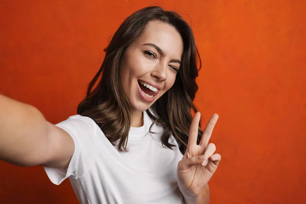 Szczęśliwa Piękna Dziewczyna Gestykulując Znak Pokoju Podczas Robienia Selfie Zdjęcie — Zdjęcie stockowe