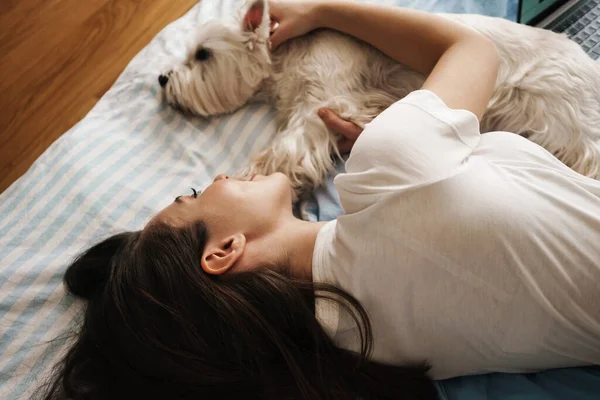 幸せな白い女性ストローク彼女の犬ながら横にベッドに家 — ストック写真