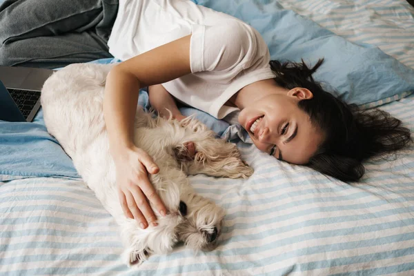 Happy White Woman Stroking Her Dog While Lying Bed Home — Stock Photo, Image