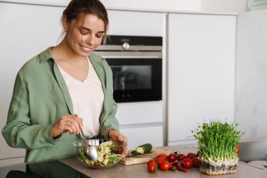 Mutfakta salata hazırlarken gülümseyen güzel kadın.