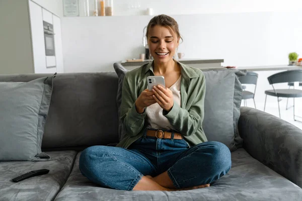 Feliz Mulher Agradável Usando Telefone Celular Enquanto Sentado Sofá Casa — Fotografia de Stock