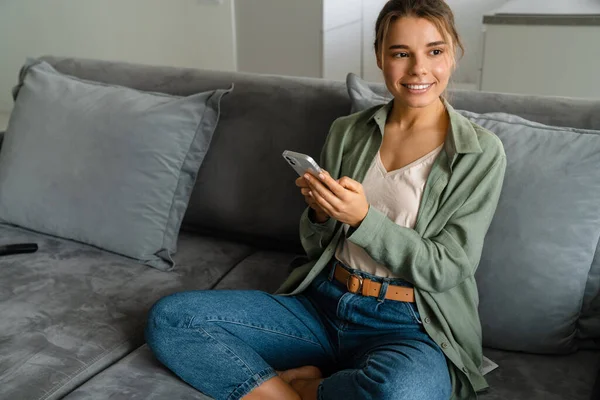 Feliz Mulher Agradável Usando Telefone Celular Enquanto Sentado Sofá Casa — Fotografia de Stock