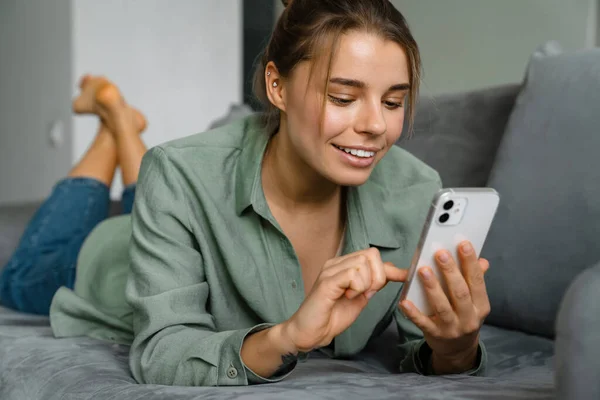 Feliz Mujer Agradable Usando Teléfono Móvil Mientras Está Acostado Sofá — Foto de Stock