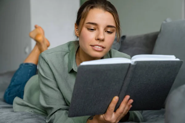 Agradable Hermosa Mujer Leyendo Libro Mientras Está Acostado Sofá Casa —  Fotos de Stock