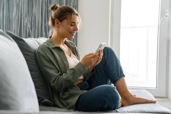Mutlu Güzel Bir Kadın Evdeki Koltukta Otururken Cep Telefonu Kullanıyor — Stok fotoğraf