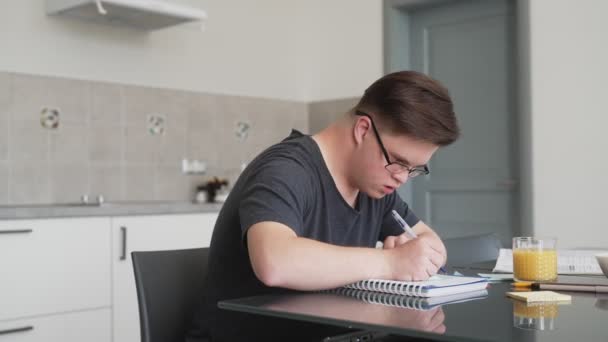 Een Gefocuste Man Met Een Bril Met Dons Syndroom Schrijft — Stockvideo