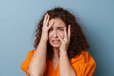 Mutsuz kızıl kadın yüzünü buruşturuyor ve mavi arka planda soyutlanıyor.