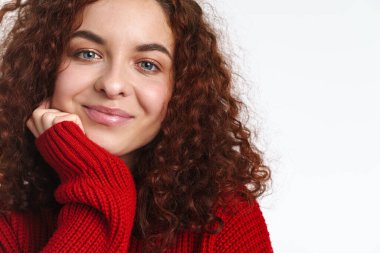 Neşeli kızıl kıvırcık saçlı, gülümseyen ve beyaz arka planda izole edilmiş kameraya bakan kız.