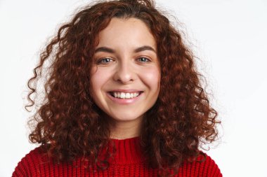 Neşeli kızıl kıvırcık saçlı, gülümseyen ve beyaz arka planda izole edilmiş kameraya bakan kız.