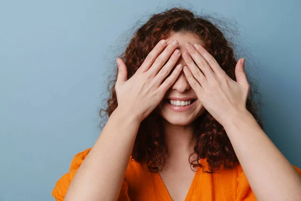 Happy Redhead Curly Girl Smiling Covering Her Eyes Isolated Blue — Stock Photo, Image