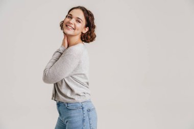 Portrait of a lovely young attractive smiling woman in casual wear posing isolated over white background
