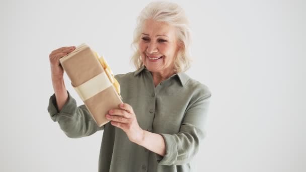 Μια Ευτυχισμένη Ηλικιωμένη Γυναίκα Κρατά Ένα Δώρο Που Στέκεται Απομονωμένη — Αρχείο Βίντεο