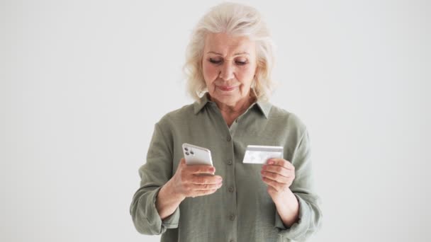 Fokuserad Äldre Kvinna Använder Sin Smartphone Samtidigt Som Hon Skriver — Stockvideo