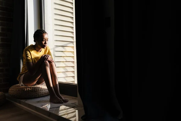 Приваблива Молода Африканська Жінка Сидить Підвіконні Вдома Розслабляючись — стокове фото