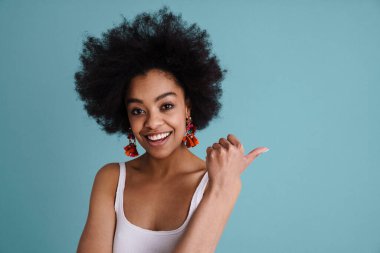 Gülümseyen Afrikalı genç bir kadın mavi arka planda kameraya bakıyor.