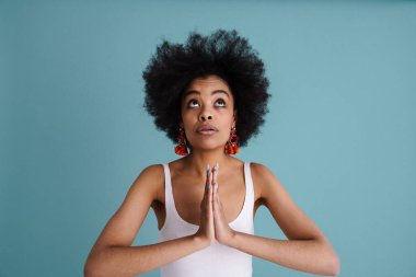 Güzel, genç Afrikalı bir kadın mavi arka planda tek başına duran bir şey istiyor.