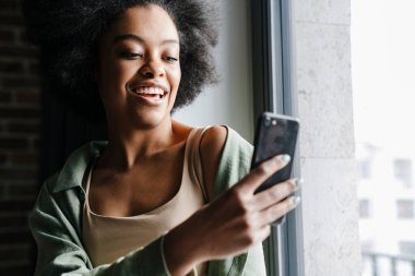 Orta yaşlı mutlu bir Afrikalı kadın cep telefonuyla resim çekiyor.