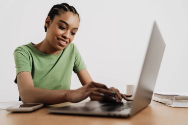 Ofiste otururken bilgisayarla çalışan gülümseyen zenci kadın.