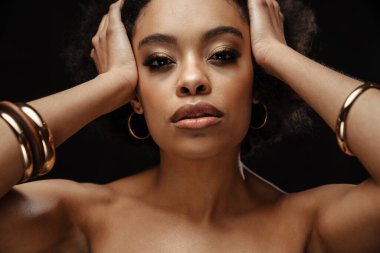 Kafasını siyah arka planda tutarken poz veren Afro-Amerikalı kadın.