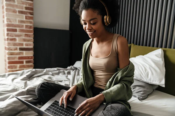 Happy Young African Woman Headphones Sitting Bed Laptop Computer Home — Stock Photo, Image