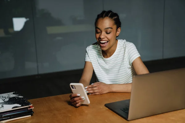 Black Laughing Woman Using Mobile Phone While Working Laptop Office — 图库照片