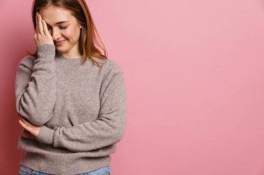 Genç kızıl mutlu kadın gülümsüyor ve yüzünü pembe arka planda soyutluyor.