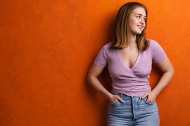 Genç kızıl mutlu kadın gülümsüyor ve turuncu duvarın ötesine bakıyor.