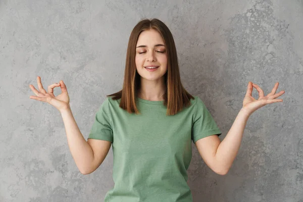 お願い美しいです素晴らしいです女の子Meditingとともに目閉じ隔離上灰色の壁 — ストック写真