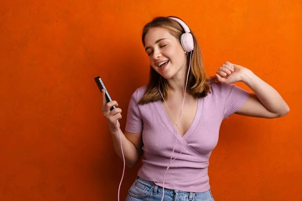 Joyful Woman Dancing While Listening Music Headphones Cellphone Isolated Orange — 스톡 사진