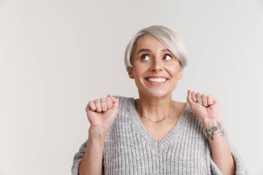 Beyaz arka planda izole edilmiş yumruklarıyla gülümseyen gri saçlı genç kadın.