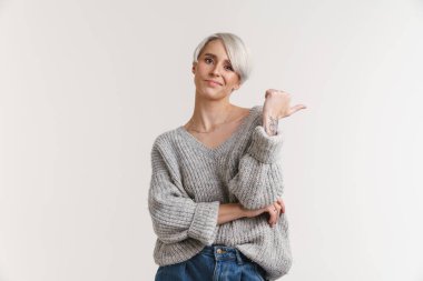 Kafası karışmış güzel gümüş kız poz veriyor ve beyaz arka planda izole edilmiş bir şekilde işaret ediyor.