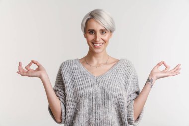 Beyaz saçlı, gülümseyen ve parmaklarını bir arada tutan genç bir kadın.